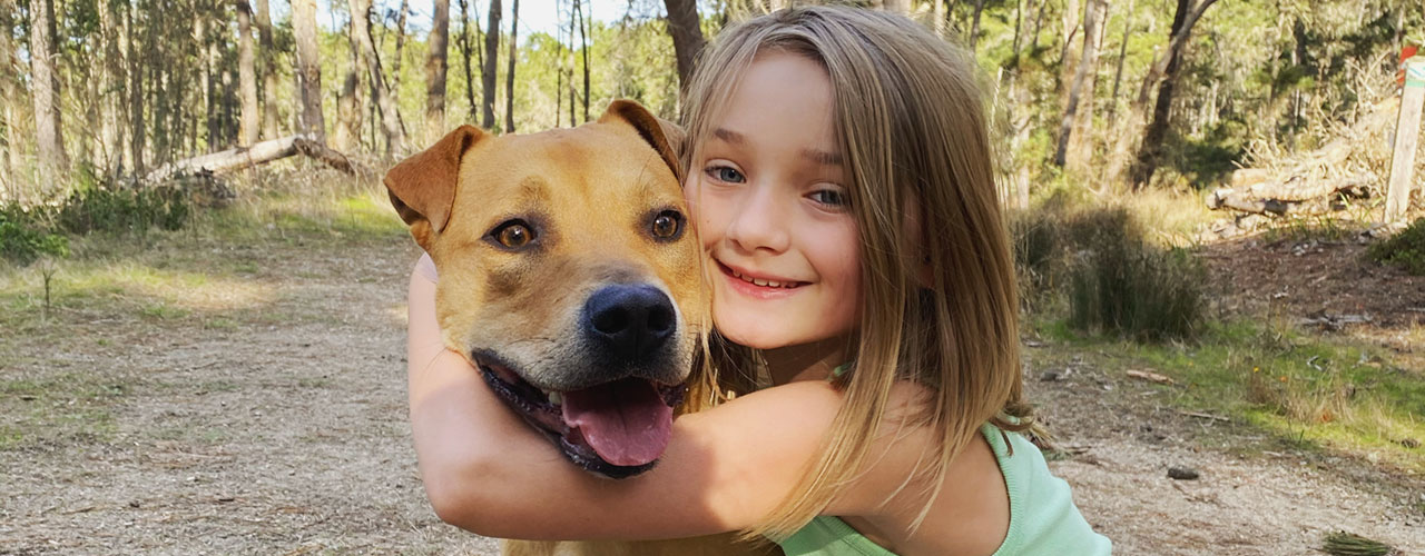 Girl-hugs-dog-in-forest_1280x500